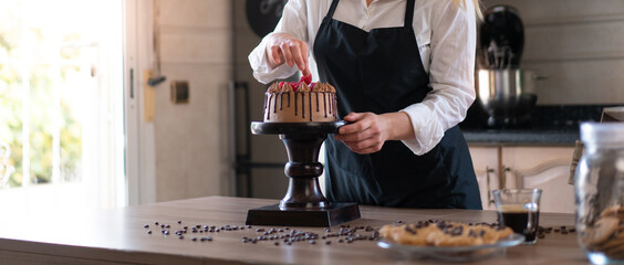 Young pastry chef cooking a delicious homemade chocolate cake with fruits in the kitchen