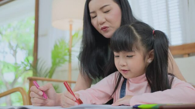 Asian young little girl enjoy drawing and painting with mother at home