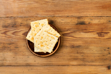Galletas saladas cuadradas dentro de un cuenco redondo de madera sobre una mesa de madera rúsica. Vista superior. Copy space