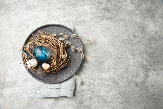 Easter nest with eggs, feathers and pussy willow twigs on a natural stone background. space for text