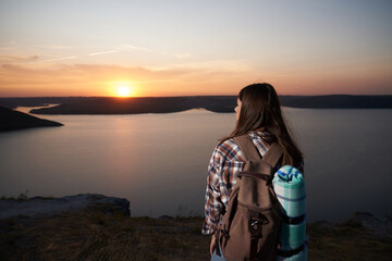 Female hiker with backpack enjoying sunset from hill
