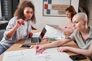 Girls making handmade posters about feminism while sitting at the table together
