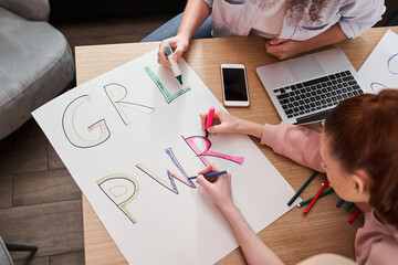 Girls drawing handmade poster with slogans about girls power at the table