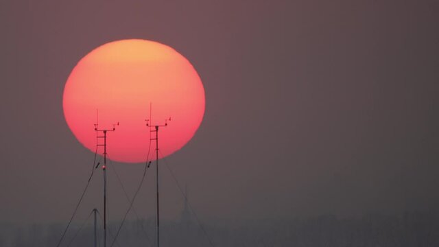 A large orange sun layer settles. Beautiful sunset, sunrise where the sun sets behind electric poles and antennas.