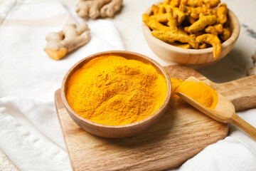 Bowl and scoop with turmeric powder on table, closeup