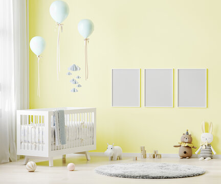 Blank poster frames mock up on yellow wall in nursery room interior background with baby bedding, soft toys, balloons, 3d rendering