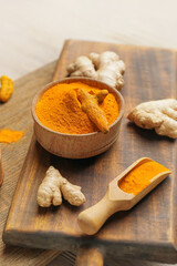 Bowl and scoop with turmeric powder on chopping boards, closeup