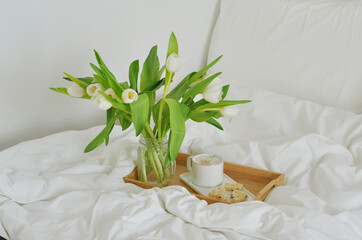 white flower in a bed with a cup of coffee