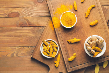Composition with turmeric powder and roots on wooden background