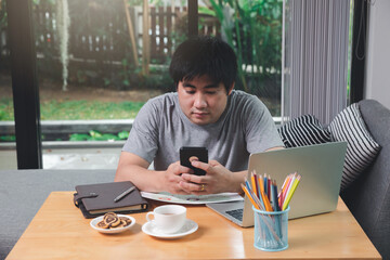 A man in casual wear using phone and working at home office.