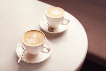Cups of coffee with latte art on table in cafe
