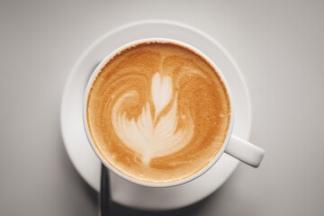 Cup of coffee with latte art on light background