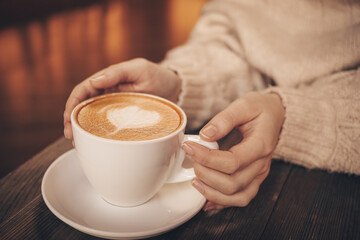 Woman with cup of latte at table in cafe