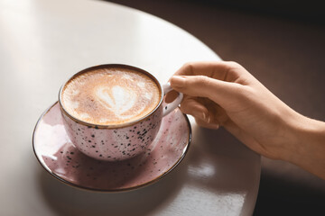 Woman with cup of latte at table in cafe