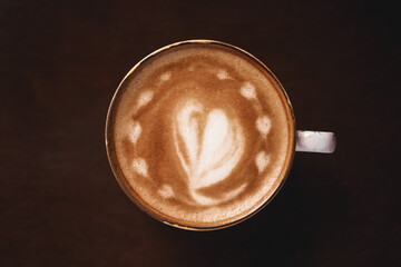 Cup of coffee with latte art on wooden background