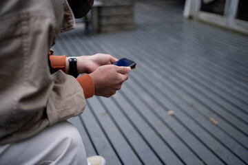 店の外でスマートフォンを触りながら開店を待つ青年