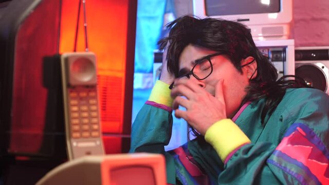 Funny retro man looking tired in front of his old vintage computer. He has trouble staying awake and concentrating. 90s 80s