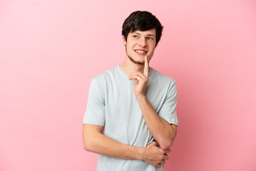 Young Russian man isolated on pink background thinking an idea while looking up