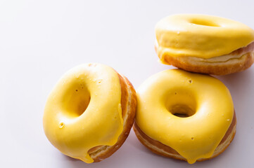 three donuts with banana filling lie on a white background, delicious breakfast, bright mood