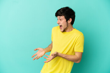 Young Russian man isolated on blue background with surprise expression while looking side