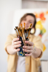 girl holding a jar with art brushes, selective focus, girl out of focus