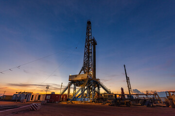 Land drilling rig in oil field during sunrise, petroleum industry