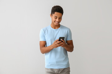African-American teenage boy with mobile phone on grey background
