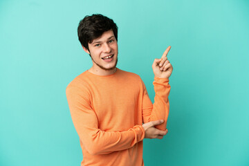 Fototapeta premium Young Russian man isolated on blue background happy and pointing up