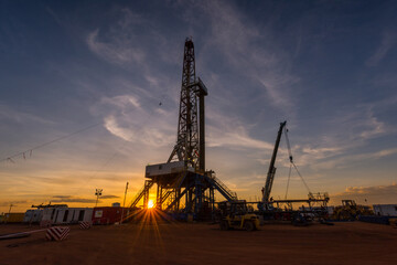 Sunset at drilling rig in oil field of petroleum industry