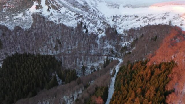 For&ecirc;t et chemins en hiver durant un coucher de soleil rose. Chemin forestier face &agrave; la Montagne. Promenade et randonn&eacute;es. Bois et chemins enneig&eacute;s. Montagnes en Auvergne dans la Cha&icirc;ne des Puys.