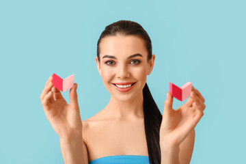 Beautiful young woman with makeup sponges on color background
