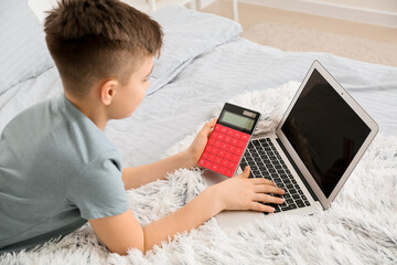 Little boy with laptop and calculator at home