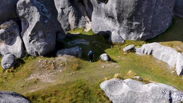 Tourist walking on grass between gigantic rock formation of Castle Hill during sunlight. Aerial top down shot.