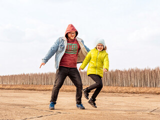 Fototapeta premium jumping man and girl child (dad and daughter) on the background of the forest in spring