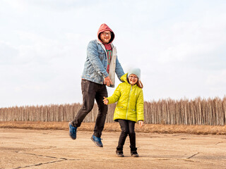 Fototapeta premium jumping man and girl child (dad and daughter) on the background of the forest in spring