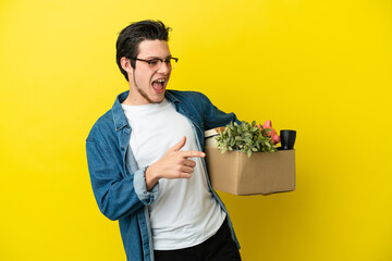 Russian Man making a move while picking up a box full of things isolated on yellow background...