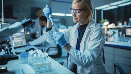 Female Research Scientist Uses Micropipette to Mix Liquids in a Sample Test Tube in a Modern Laboratory. Scientists are Conducting DNA Research with the Help of Technology, Microscopes and Computers.