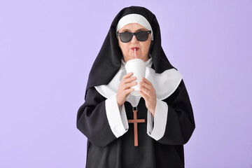 Funny senior nun with soda on color background