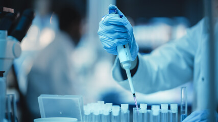 Close Up of a Research Scientist Using Micropipette to Mix Liquids in a Test Tube in a Modern...