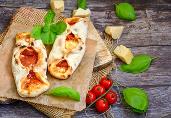 Home made italian  mini calzone  salami pizza with  tomatoes, mozzarella and parmesan cheese and fresh basil 