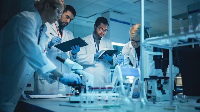 Team of Medical Research Scientists Have Meeting and Conduct Experiments with Help of DNA Samples in Test Tubes and Microscope Slides. Applied Science Laboratory with Diverse Multicultural Colleagues.