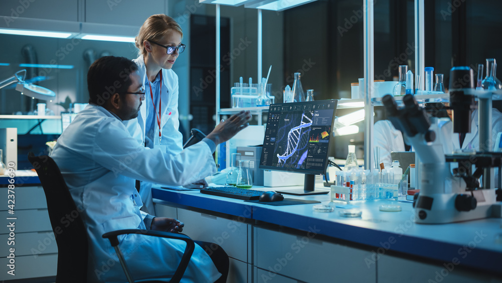 Wall mural female research scientist with bioengineer working on a personal computer with screen showing dna an