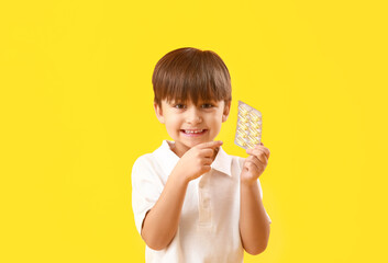 Little boy with fish oil on color background