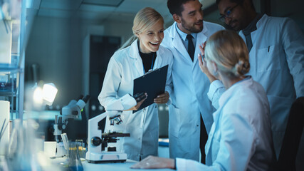 Happy Female Reseach Scientist Makes an Important Discovery While Researching Samples Under the Microscope. Happy Colleagues Celebrate it and Share Success with Fellow Bioengineers.