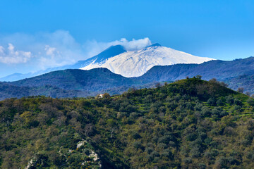 green slopes under the Etna volcano Snow-covered in a beautiful early spring sky