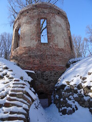 Ruin from bricks covered by snow in sunlight in Pokoj in Poland.