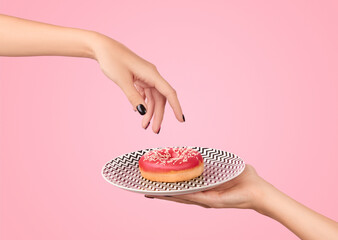 Womans hand takes tasty donut on pink background. Mockup template for bakery