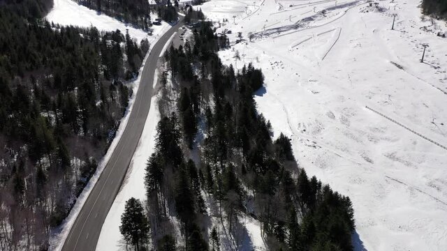 Route de montagne dans une station de ski en Auvergne, France. Route sinueuse dans la neige. Chemin dans la foret vers la station de ski. Aller skier dans la montagne.
