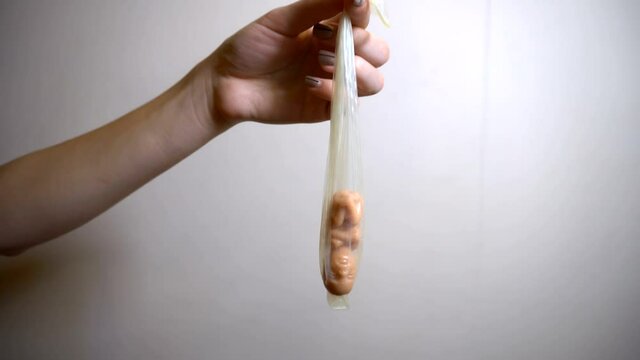 A girl holds a used condom with an embryo