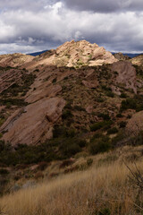 Rock formations under moody skies in the desert.  Sunlight breaking through the clouds providing dramatic light on the scene. 